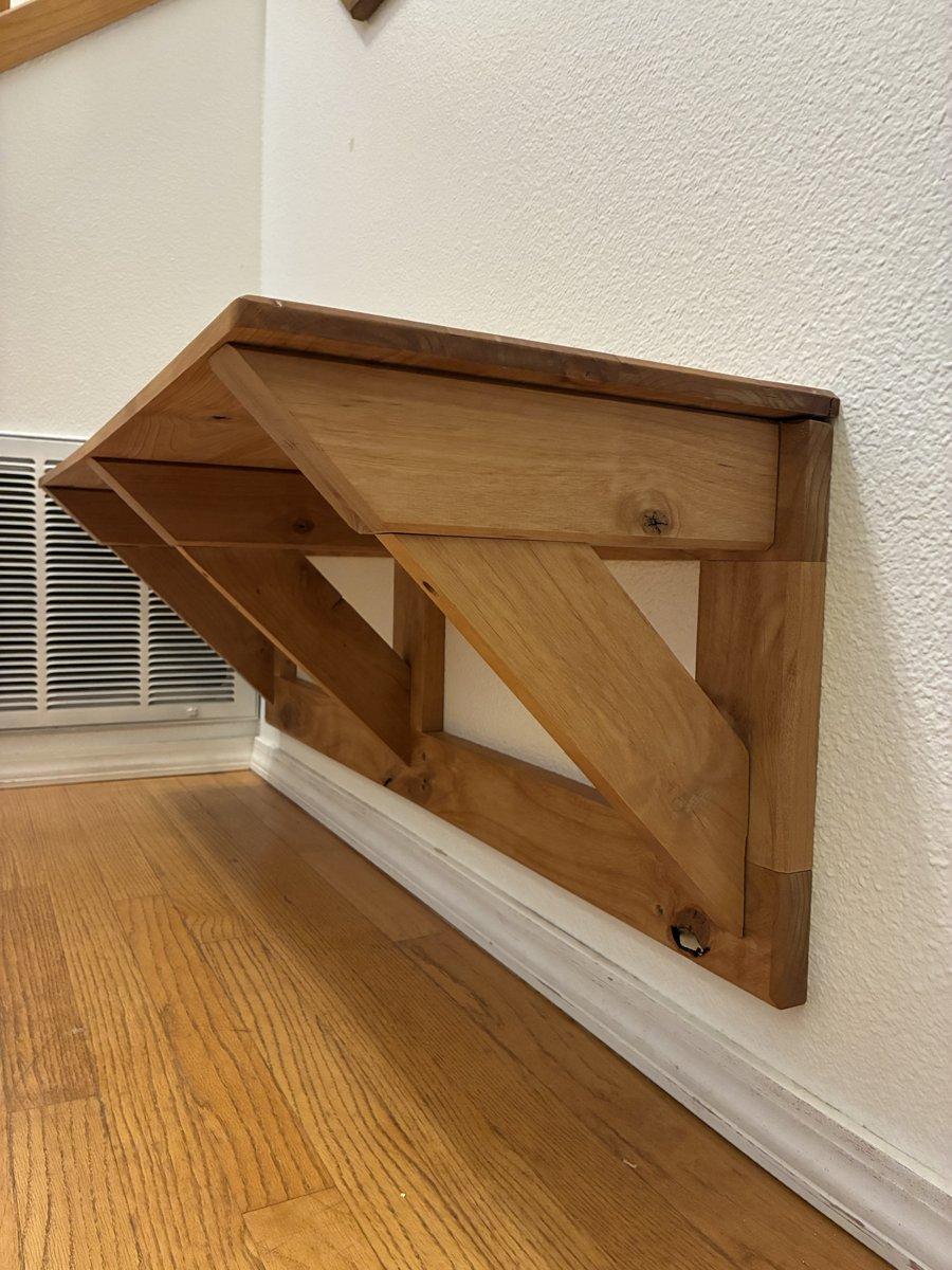 A wall mounted bench. This was built using a toungue-and-groove panel meant for a table top, but it wouldn't stay flat. When life gives you lemons, you screw it down and make a bench.